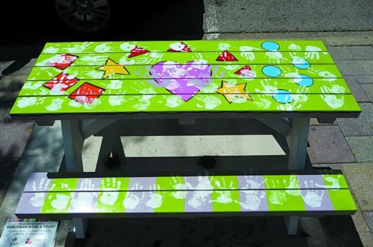 A green picnic table with hand painting and colorful graffiti.