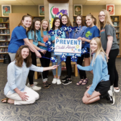 10 members of PCA North Dakota hold blue pinwheels and a "Prevent child abuse America" sign.