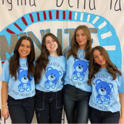 4 Sigma Delta Tau sisters wearing blue t shirts with teddy bears that say "Sigma Delta Tau - Prevent Child Abuse America."