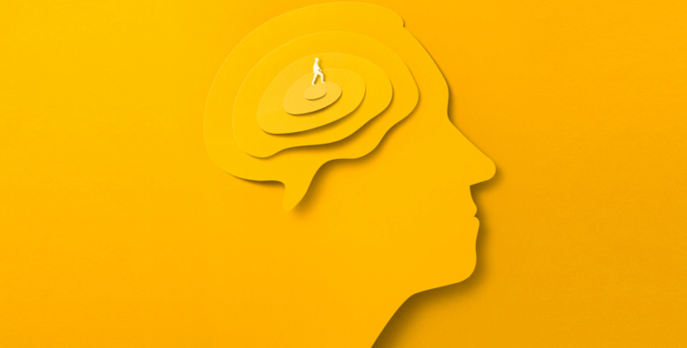 A yellow cut out of a human head profile on a yellow background in a paper cut out style, with layers descending in size creating a brain shape with a figure of a person in the center.
